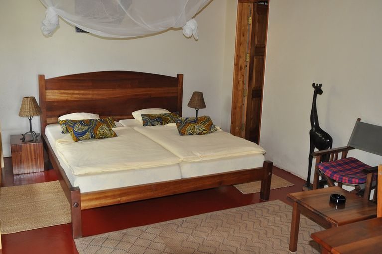 Double bed with carved headboard in a Mbega room
