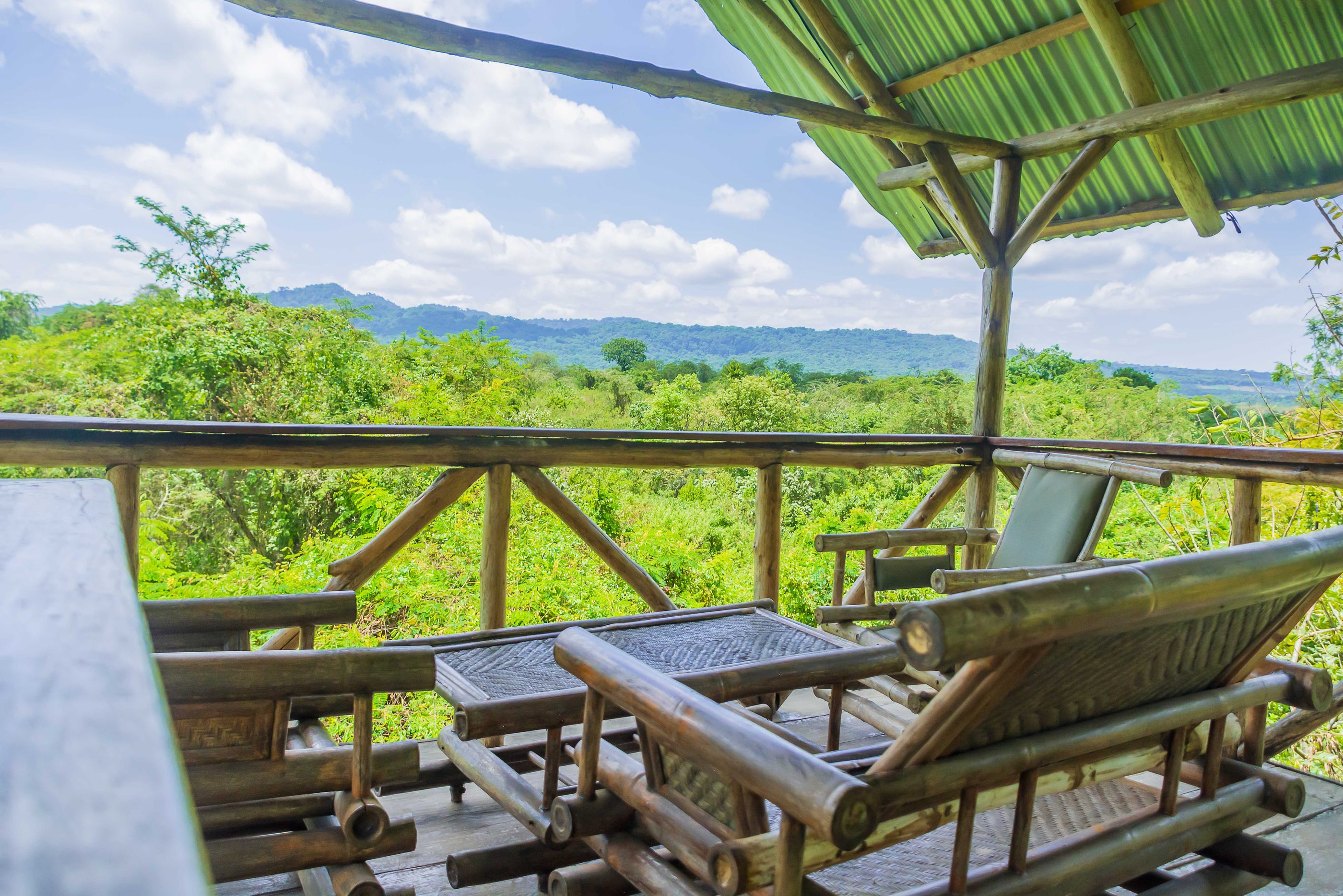 Bamboo loungers on a shaded deck at the lodge, looking out over the forest to the hills